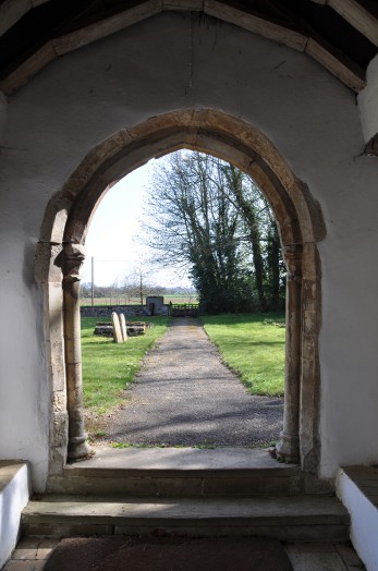 A view from inside looking out over the churchyard at Belchamp Otten